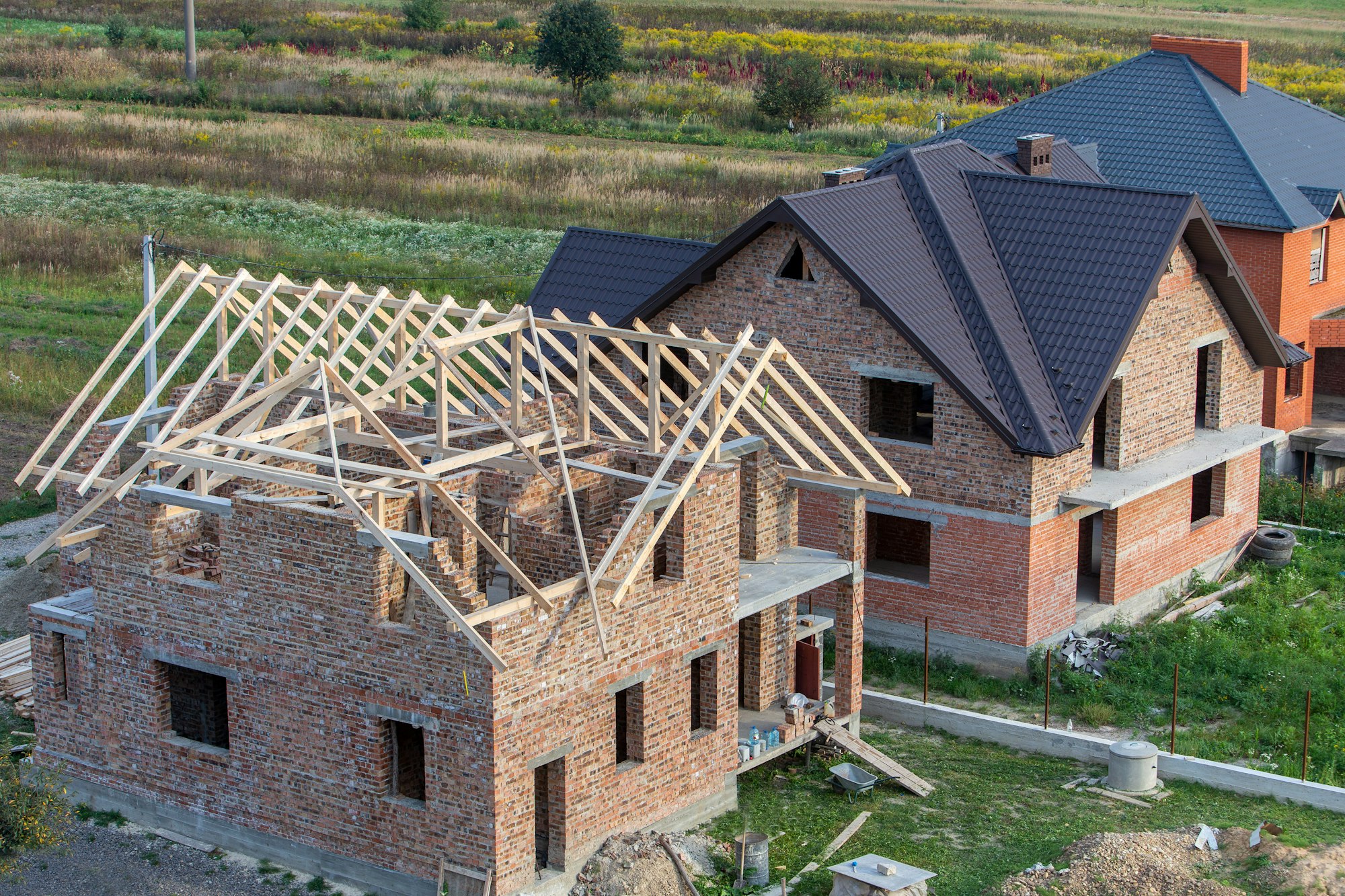 Unfinished brick house with wooden roof structure under construction